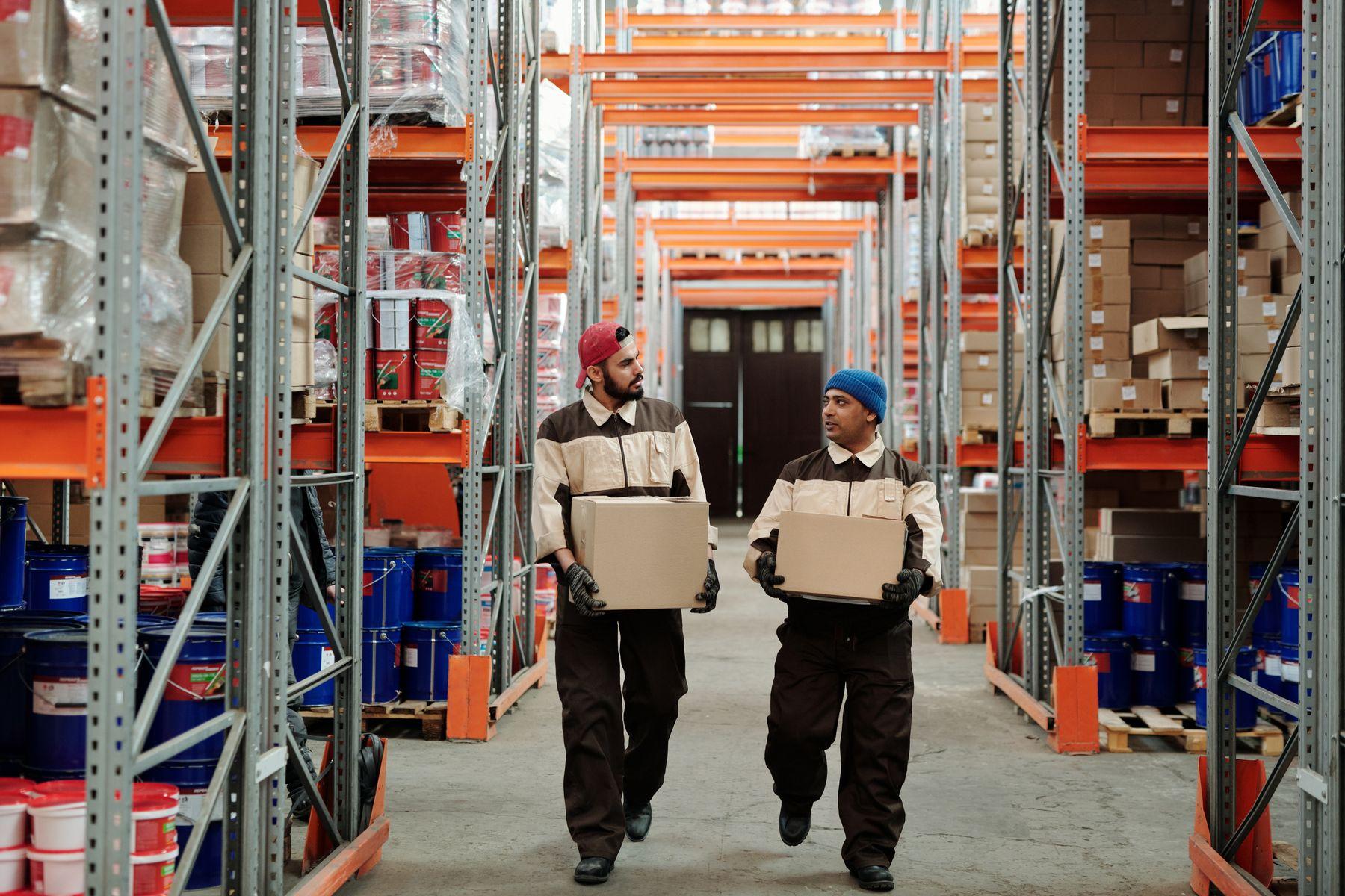 Uniformed warehouse workers carrying boxes together